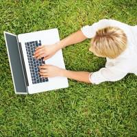 Persoon ligt op gras met laptop